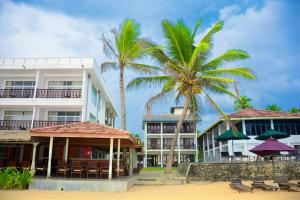 eine Gruppe von Gebäuden am Strand mit Palmen in der Unterkunft Ranmal Beach Hotel in Hikkaduwa