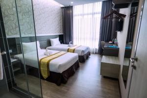 a hotel room with two beds and a glass wall at Indra Hotel Ipoh in Ipoh