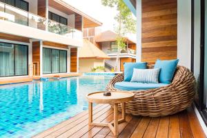 a wicker chair sitting on a deck next to a swimming pool at AKIRA Lipe Resort in Ko Lipe