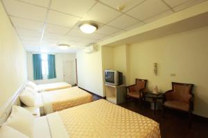 花蓮市にあるYong Qi Hotelのベッド2台とテレビが備わるホテルルームです。