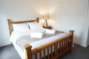 a bedroom with a wooden bed with two towels on it at Ben's Place - modern & convenient in Mansfield