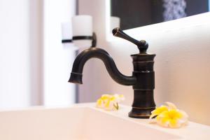 - un lavabo avec un robinet noir et des fleurs jaunes dans l'établissement Azure Beach Boutique Hotel, à Grand Baie