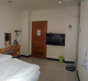 een slaapkamer met een bed en een flatscreen-tv bij Wooden Man Homestay in Taitung