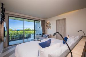 The SIS Kata, Resort - SHA Plus في شاطئ كاتا: غرفه فندقيه بسرير وشرفه