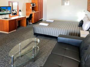 ein Hotelzimmer mit einem Bett, einem Schreibtisch und einer Couch in der Unterkunft Leeton Heritage Motor Inn in Leeton