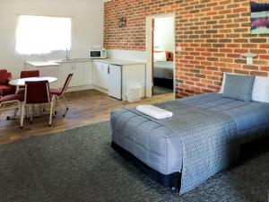 ein Schlafzimmer mit einem Bett und einer Ziegelwand in der Unterkunft Leeton Heritage Motor Inn in Leeton