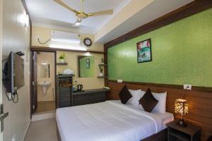 a bedroom with a white bed and a green wall at Gems 9 Airport Hotel in Nedumbassery