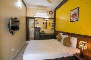 a bedroom with a white bed and a yellow wall at Gems 9 Airport Hotel in Nedumbassery