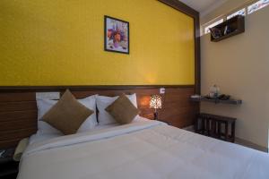 a bedroom with a white bed with a yellow wall at Gems 9 Airport Hotel in Nedumbassery