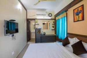 a bedroom with a bed and a television and a bathroom at Gems 9 Airport Hotel in Cochin