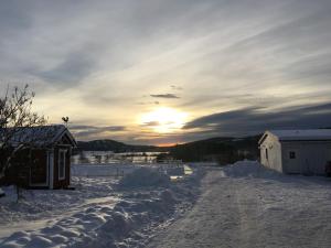 una carretera cubierta de nieve con la puesta de sol en el fondo en Lilla Vrån, en Lerbäcken