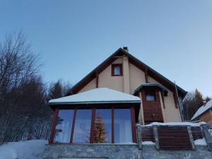 una casa con techo cubierto de nieve y banco en Planinski Biser, en Kopaonik