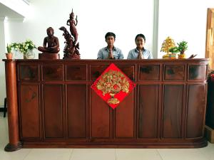 two men are standing behind a wooden counter with a red box at Lucky Hostel in Battambang