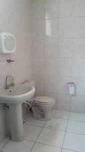 a white bathroom with a toilet and a sink at Hostel Famille Brun Trevo in São João da Boa Vista