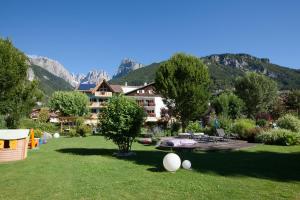 a garden with a hotel and mountains in the background at Garden Hotel Bellariva in Molveno