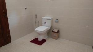 a bathroom with a toilet with a red rug at Sunworld Villa in Unawatuna