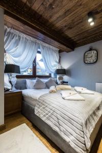 - une chambre avec un grand lit et une horloge murale dans l'établissement Apartament Szymaszkowa Relax Ski Odkryj Zakopane, à Zakopane