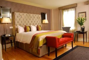 um quarto de hotel com uma cama e uma cadeira vermelha em Benedicts Hotel em Belfast