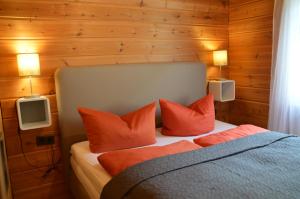 una camera da letto con un letto con cuscini arancioni e due luci di Family 7 a Ulmen
