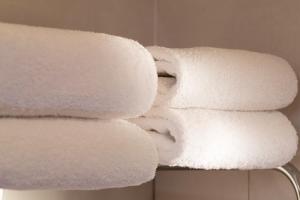 einen Haufen weißer Handtücher auf einem Regal im Bad in der Unterkunft Europe Hotel Paris Eiffel in Paris