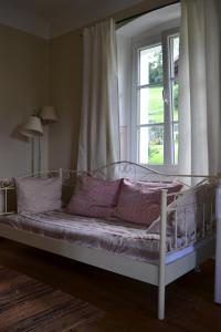 a bed with purple pillows in a room with a window at Altes Pfarrhaus Altersberg in Trebesing
