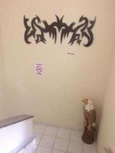 un oiseau sur un mur avec un panneau interdisant de fumer dans l'établissement Pousada Aquino, à Sobral