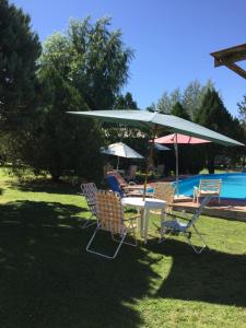 a table and chairs with an umbrella next to a pool at La Matilde in Villa Ciudad de America