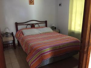a bedroom with a bed with a colorful striped blanket at La Matilde in Villa Ciudad de America +27 photos