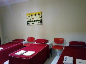 a room with three beds and red chairs and a painting at Pousada Aquino in Sobral