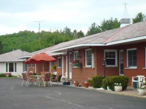 a house with a patio with chairs and an umbrella at Mountain View Motel in Barrys Bay