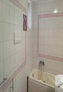 ein weiß gefliestes Bad mit einer Badewanne und einem Spiegel in der Unterkunft Il sorriso in Salerno