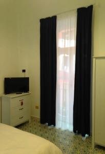 Schlafzimmer mit einem Bett, schwarzen Vorhängen und einer Kommode in der Unterkunft Il sorriso in Salerno