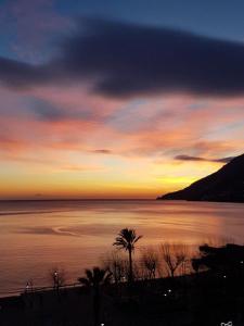 a sunset over a body of water with a palm tree at B&B Palazzo Montesanto in Maiori