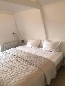 ein weißes Bett mit weißer Bettwäsche und Kissen in der Unterkunft Koningshof XL in Alkmaar