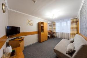 a living room with a couch and a flat screen tv at Paradise Hotel in Gomel