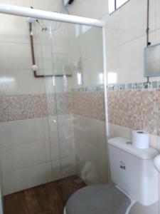 a bathroom with a toilet and a glass shower at Hospedagem Navegantes in Navegantes