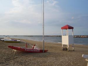 una piccola barca sulla spiaggia con una torre di guardia di Residenza Nobel Appartamenti a Rimini