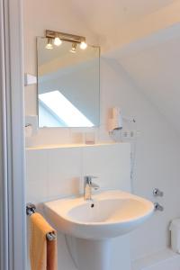 a white bathroom with a sink and a mirror at Gasthaus Jütte in Ebergötzen