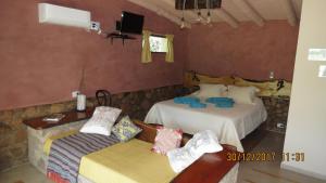 1 dormitorio con 2 camas, sofá y TV en Cabañas Entre Verde, en Los Hornillos