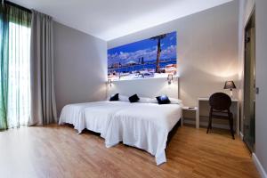 a bedroom with a white bed with a painting on the wall at Hostal BCN Ramblas in Barcelona