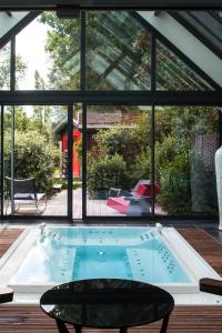 a swimming pool in a house with a large window at La Mare aux Oiseaux, The Originals Collection (Relais du Silence) in Saint-Joachim