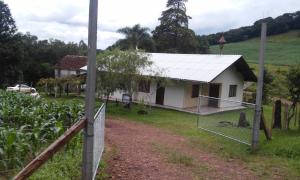 ein kleines weißes Haus mit einem Zaun davor in der Unterkunft Sítio Kanisfluh in Treze Tílias