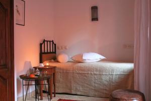 - une chambre avec un lit aux murs roses et 2 tables dans l'établissement Riad Honey, à Marrakech