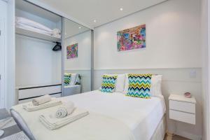 um quarto com uma grande cama branca com toalhas em Be Paulista's Studios em São Paulo