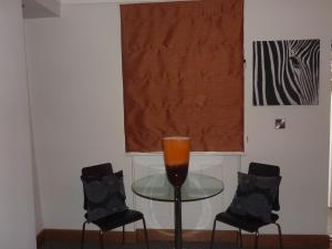 a glass table with two black chairs and a window at Hewlett Apartments in Cheltenham