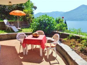 einen Tisch und Stühle mit einem Tisch und einem Sonnenschirm in der Unterkunft casa camelie in Pino Lago Maggiore