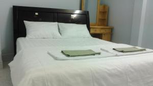 Una cama blanca con dos toallas plegables. en VKS Family Surfer House, en Phan Thiet