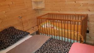 - une chambre avec lit bébé dans une cabane en rondins dans l'établissement Agroturystyka Polana Harmonii, à Przytoczna 