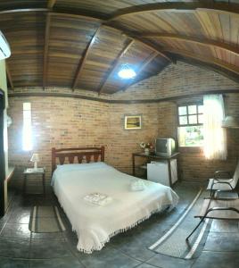 a bedroom with a large bed in a brick wall at Pousada Itupava in Morretes
