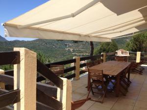 a patio with a table and chairs under a white umbrella at Villa Romarin in Partinello